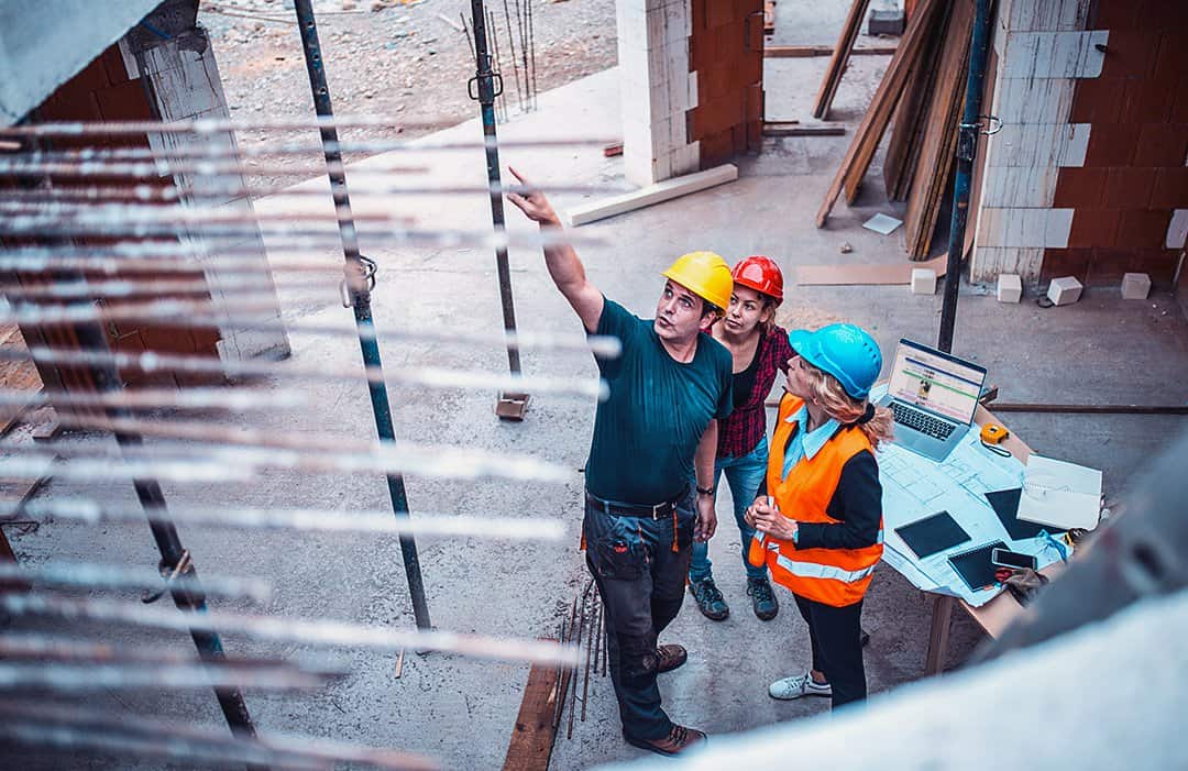 Construction workers on site using Smartsheet on a laptop